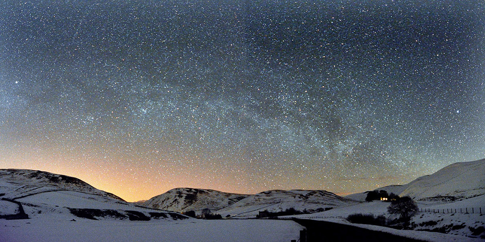 A star studded sky over snowy hills